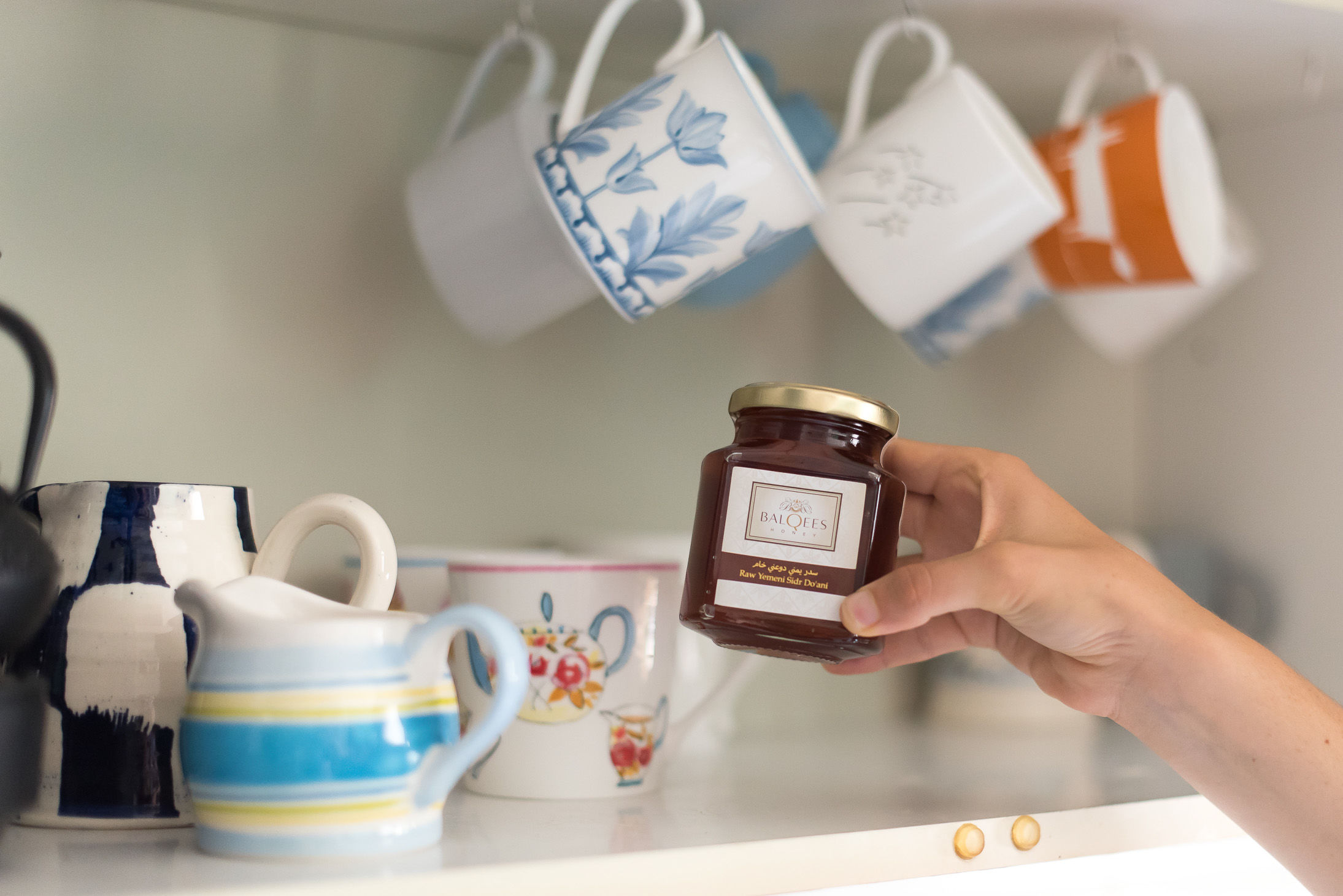 hand putting jar of raw honey into storage cupboard