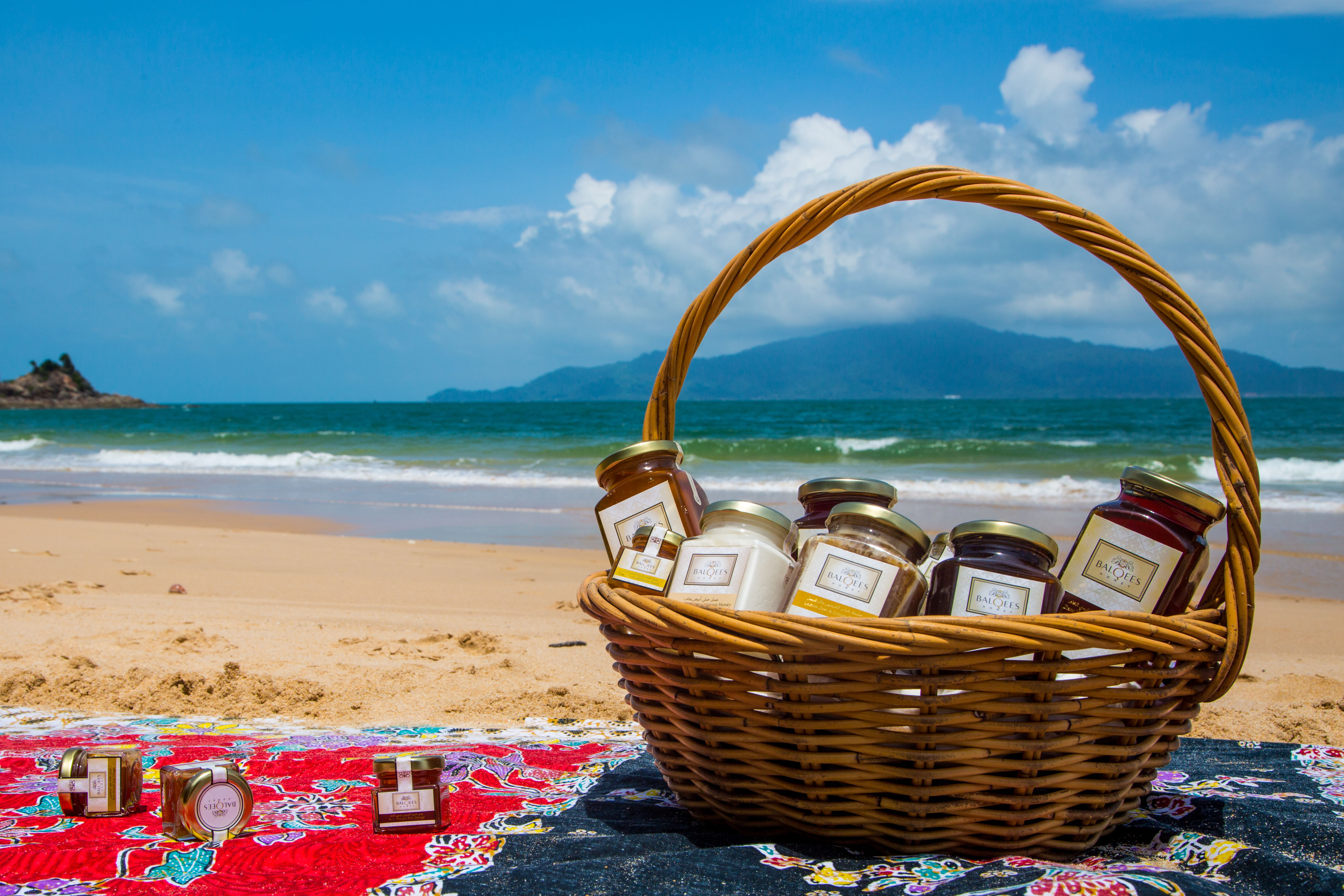 jars of raw honey in a basket on a beach