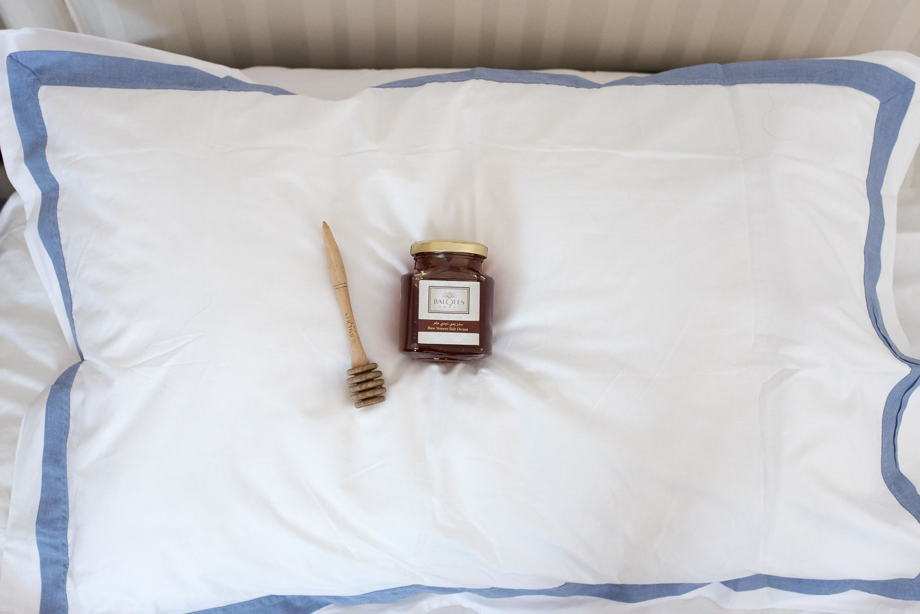 jar of raw honey and a honey drizzler on a pillow