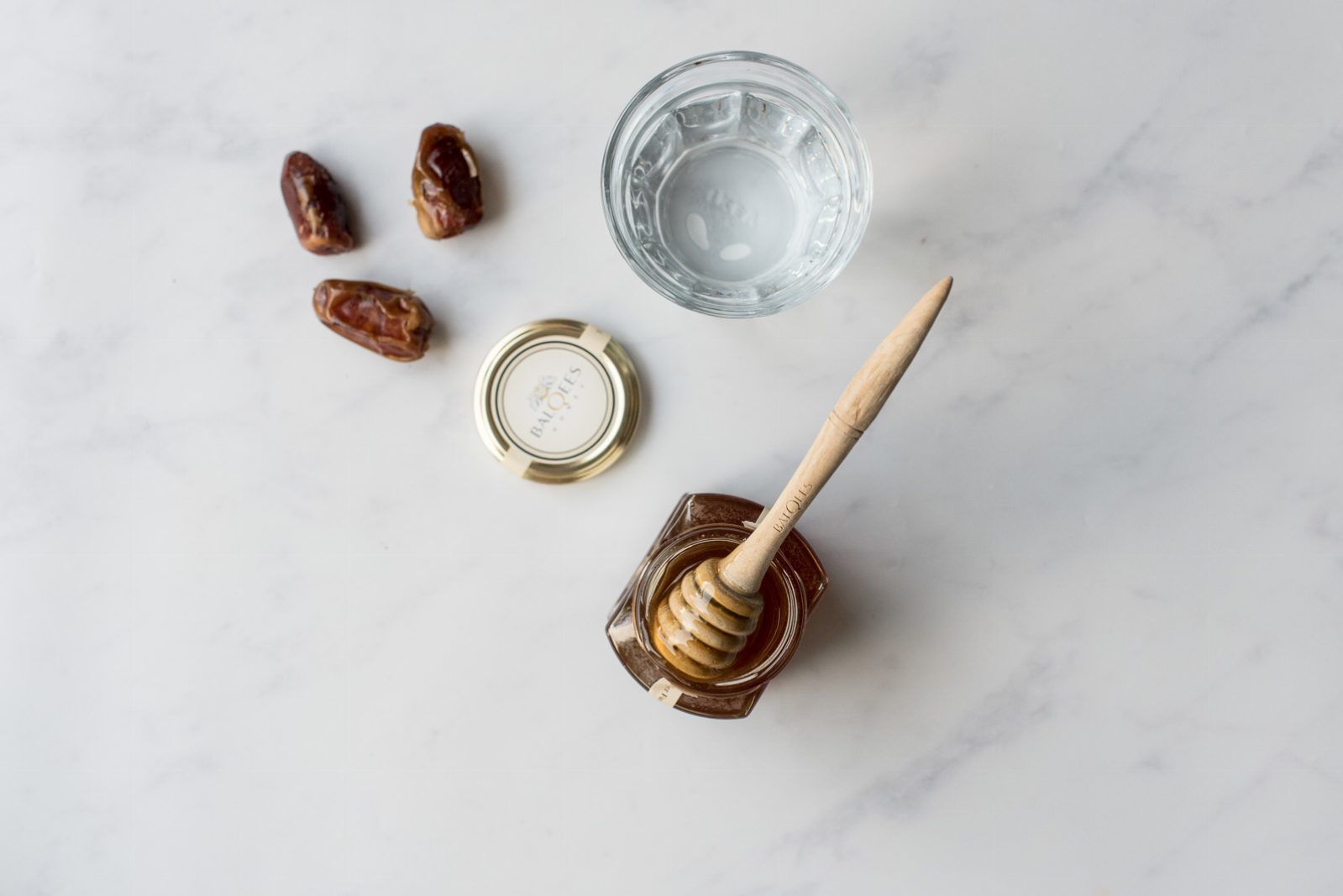 jar of honey, glass of water and dates