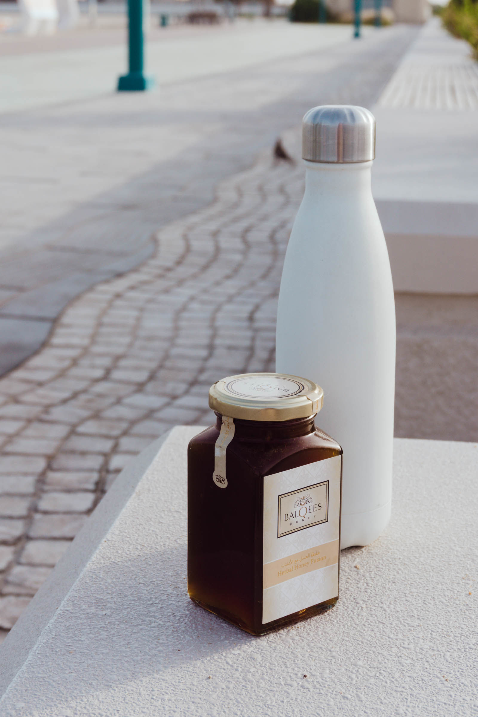 Raw honey with a water bottle by a running track