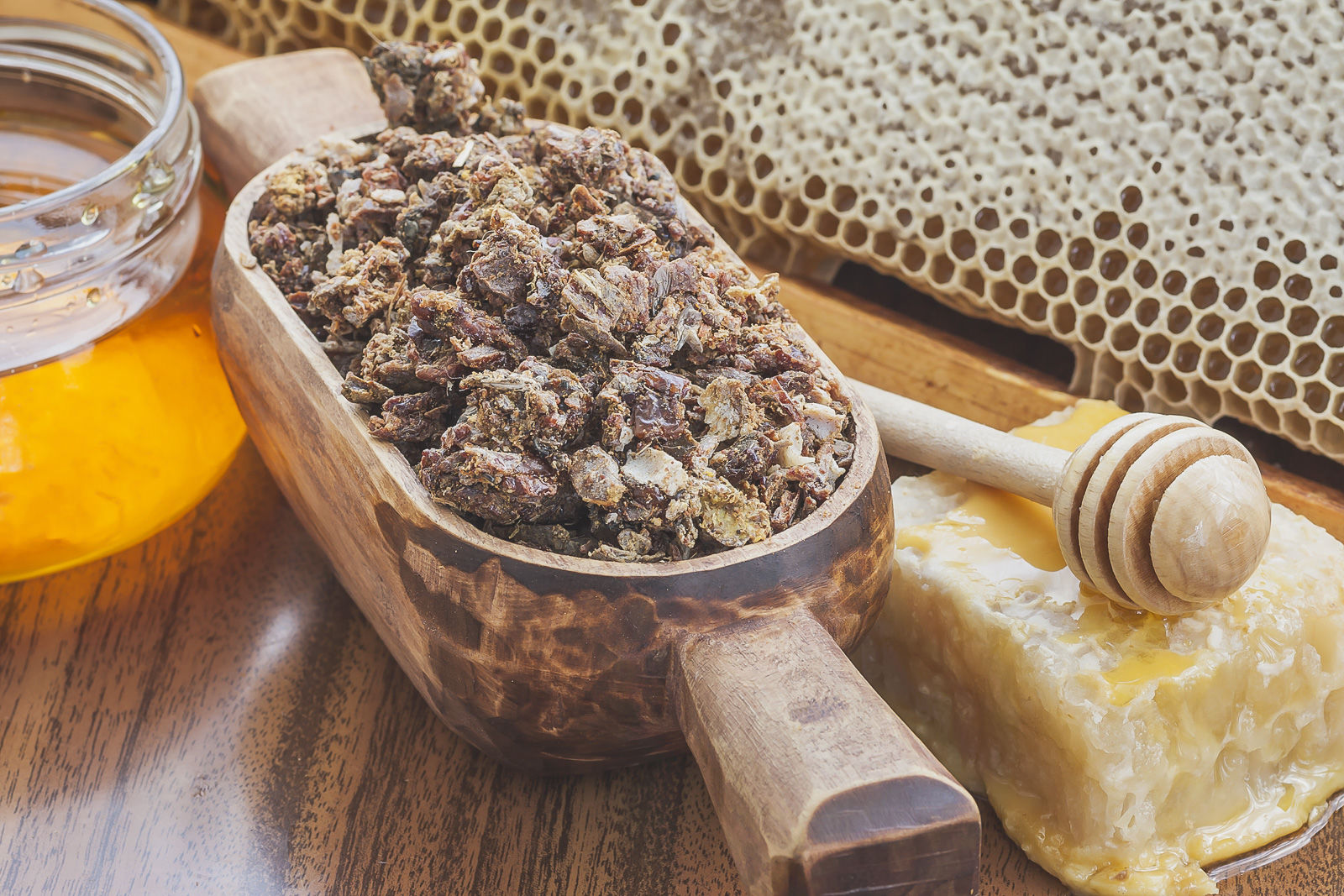 a wooden scoop full of propolis, honeycomb and beeswax